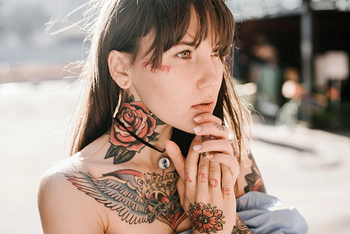 A tattooed person with hands clasped under their chin 