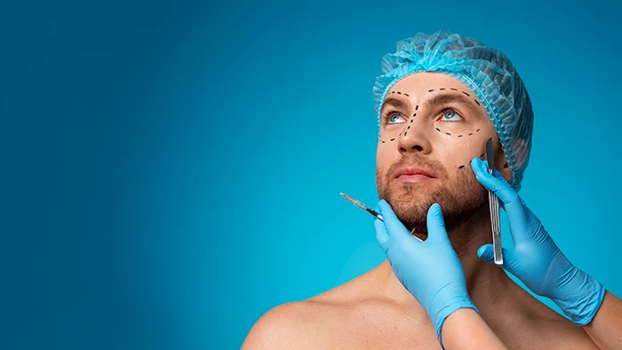 A cosmetic surgeon holding a man’s face with tools in the hands and markings on his face