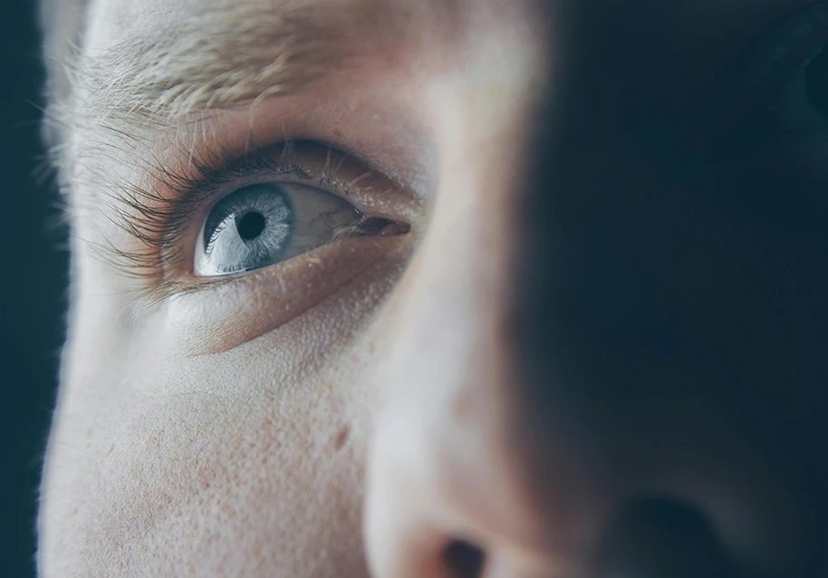 A close-up shot of a person with blue eyes and eye bags