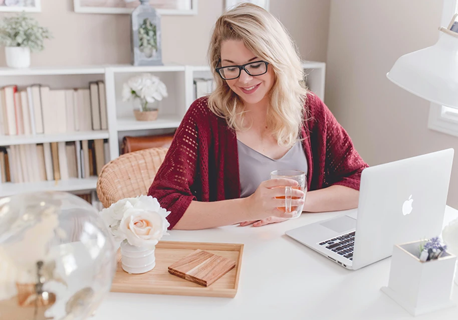a woman is having tea and using a laptop